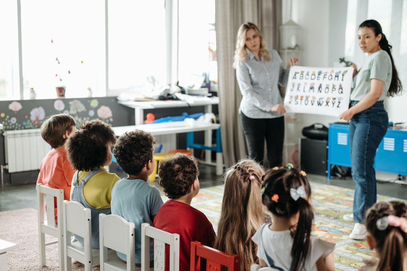 Nursery teachers leading a class of young children